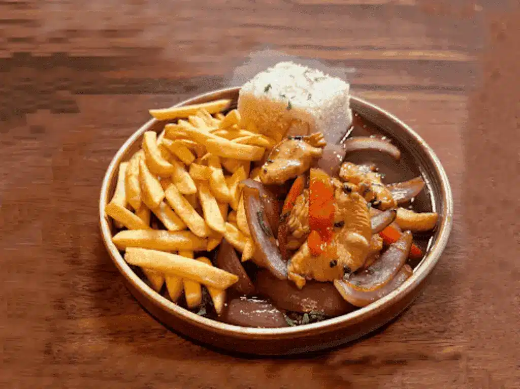 Peruvian chicken lomo saltado with fries and rice on a round ceramic plate - Manta Restaurant